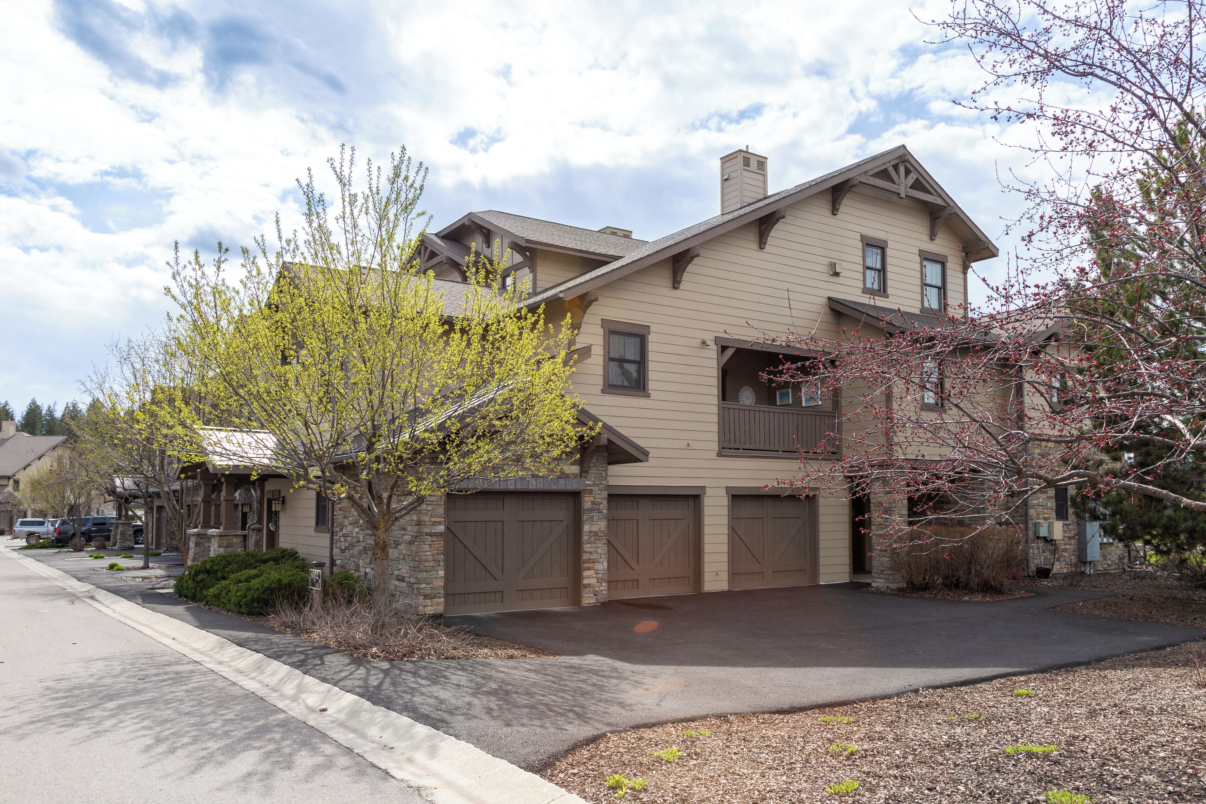 A two-story house with a garage, a driveway, and a well-maintained lawn.