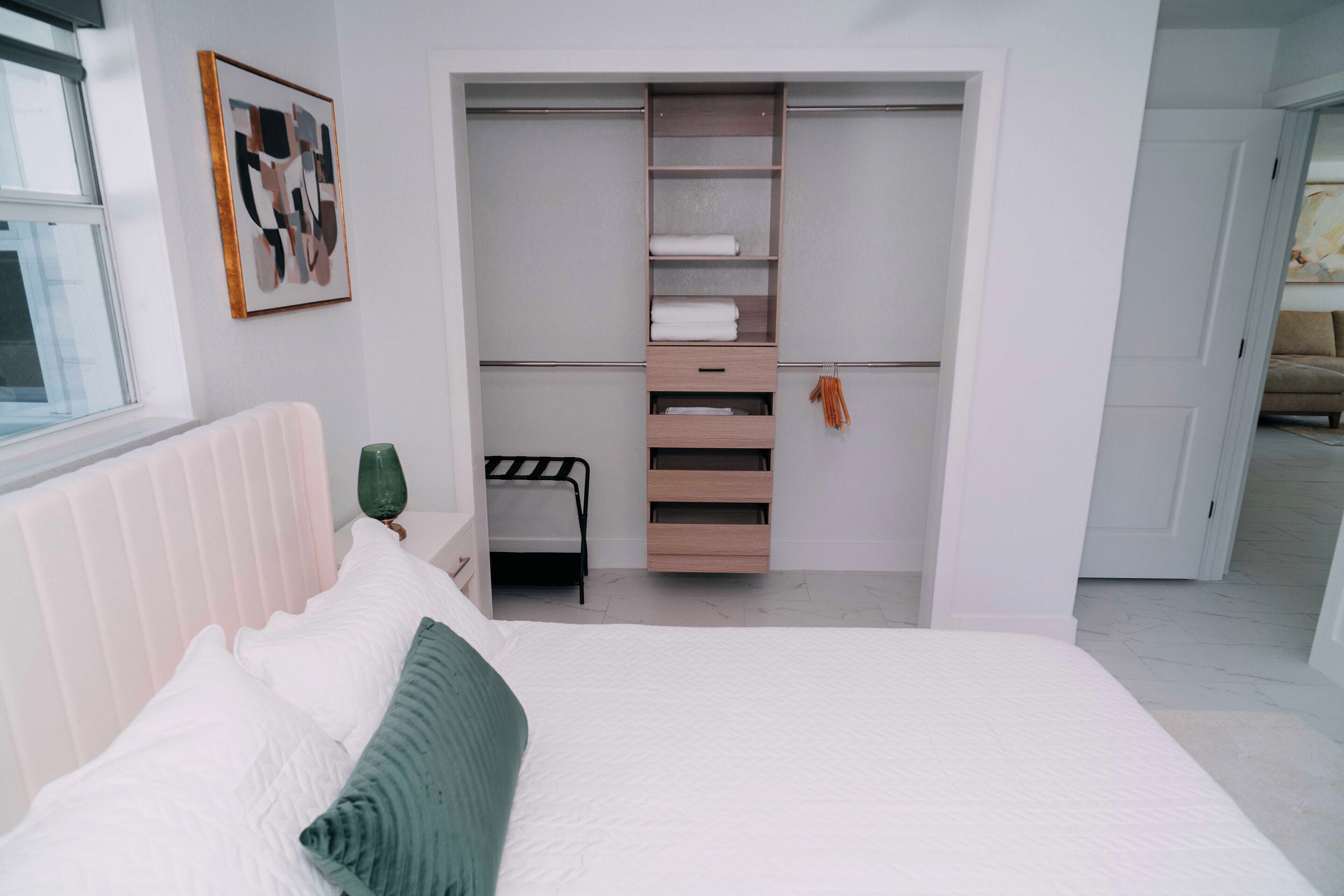 A bedroom with a bed, a bedside table, a radiator, a wardrobe, and a door leading to another room.