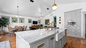 Una cocina amplia con una isla grande, armarios blancos y una lámpara colgante moderna.