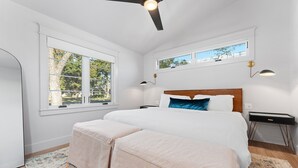 A bedroom with a large bed, two bedside tables, a ceiling fan, and a window with a view of trees. - Boxwoods | Pool | Beautiful Interior (Fredericksburg)