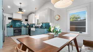 A modern kitchen with blue cabinets, a wooden dining table, and a large window. - Boxwoods | Pool | Beautiful Interior (Fredericksburg)
