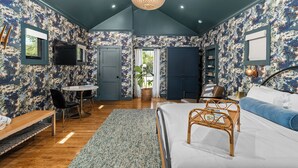 Ein Schlafzimmer mit Bett, Nachttisch, Sessel und einem Fenster mit Vorhängen.