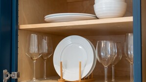 Ein Schrank mit Regalen, auf denen weiße Teller und Weingläser stehen.