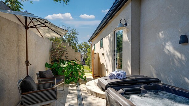 Ein Wellnessbereich mit Whirlpool, Sitzgelegenheiten und Sonnenschirm.