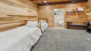 Ein Zimmer mit Holzwänden, zwei Einzelbetten, einer Bank und einem Regal mit Handtüchern.