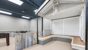 Ein modernes Zimmer mit einer gebogenen Sitzbank, einem kleinen Tisch und einem Fenster mit Jalousien.