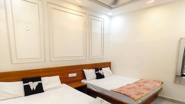 Hotellihuone, jossa on kaksi sänkyä, puiset päätylevyt, valkoiset seinät ja kattotuuletin.