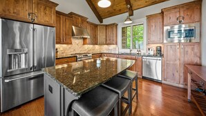 A spacious kitchen with wooden cabinets, stainless steel appliances, and a large island with bar stools. - Resort Home–Scenic Views-Whispering Ridge Estate (Boone)