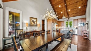 A spacious kitchen with wooden cabinets, a large island, and a modern chandelier. - Resort Home–Scenic Views-Whispering Ridge Estate (Boone)