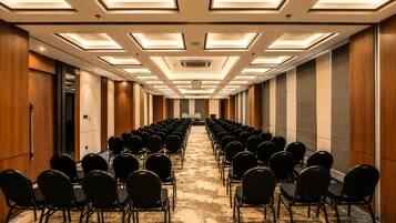 A conference room with rows of chairs, a long table, and a ceiling with recessed lighting.