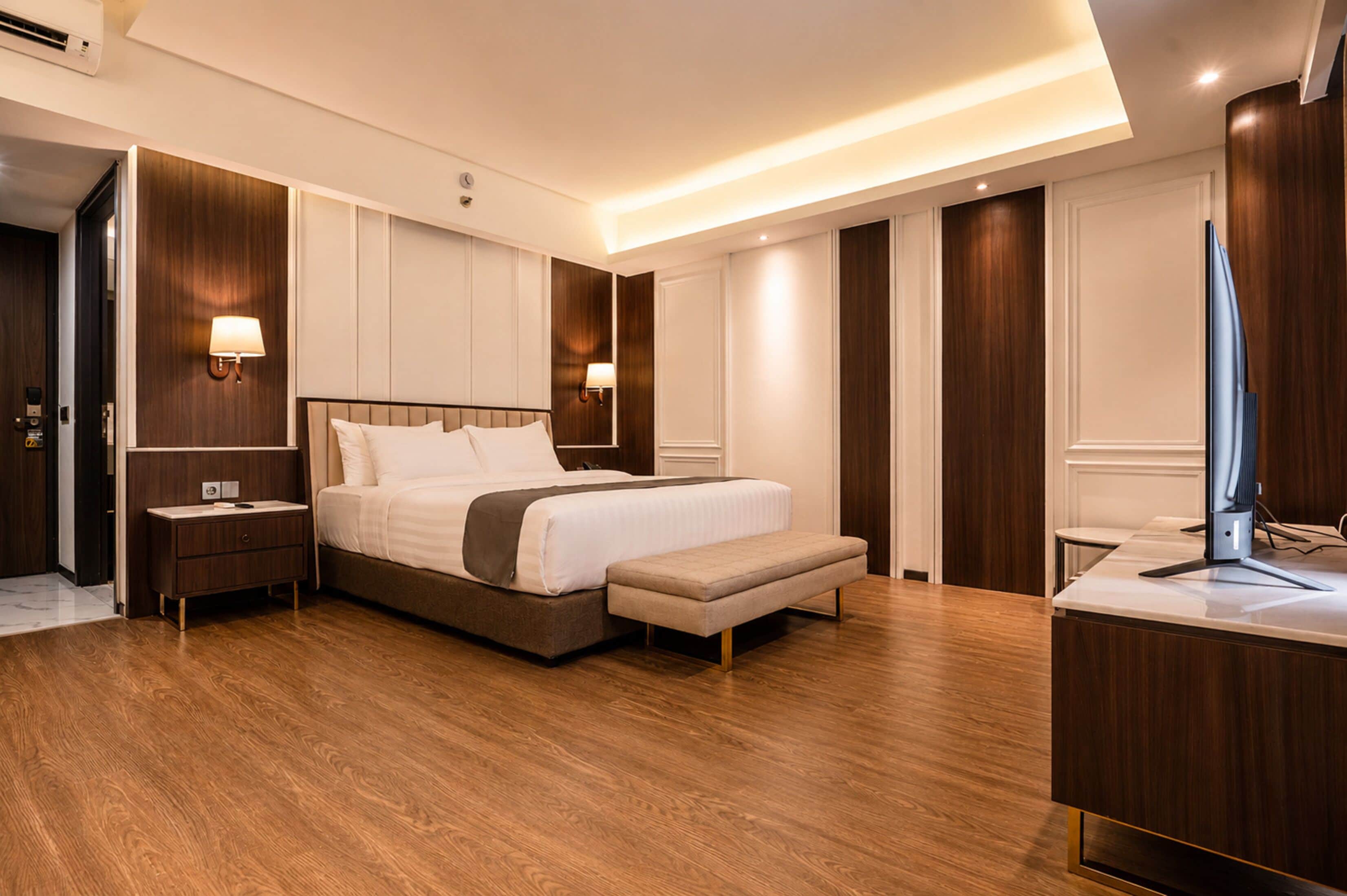 A modern hotel room with a large bed, bedside tables, a desk, and a television.
