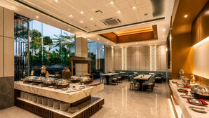 A modern restaurant with a marble counter, dining tables, and a view of greenery outside. - Arkadewi Boutique Hotel Prawirotaman (Yogyakarta)