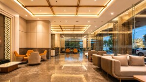 A modern lobby with a marble floor, seating areas, and a glass wall offering a view of the street. - Arkadewi Boutique Hotel Prawirotaman (Yogyakarta)