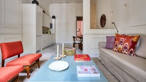 Uma sala de estar moderna com uma mesa de centro azul, cadeiras vermelhas, um sofá bege e uma estante de livros.