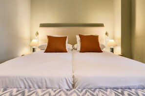 A double bed with white linens and two brown pillows, flanked by two bedside lamps. - Adriano 1.2 by Home at Homes (Sevilla)