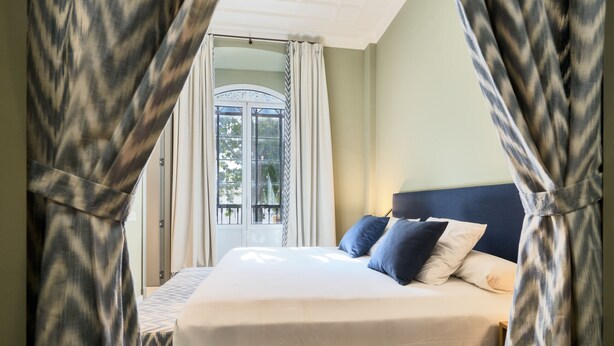 Ein Schlafzimmer mit Bett, Vorhängen und einem Fenster.
