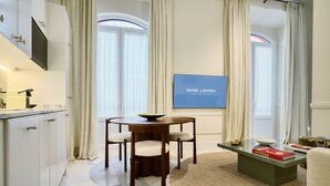 A modern living room with a dining area, a flat-screen TV mounted on the wall, and a large window with curtains. - Adriano 1.4 by Home at Homes (Sevilla)