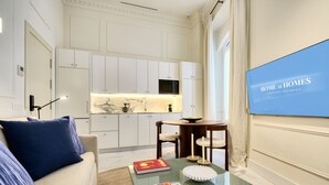 A modern living room with a glass coffee table, a sofa with blue cushions, a dining table with candles, and a kitchen in the background. - Adriano 1.4 by Home at Homes (Sevilla)