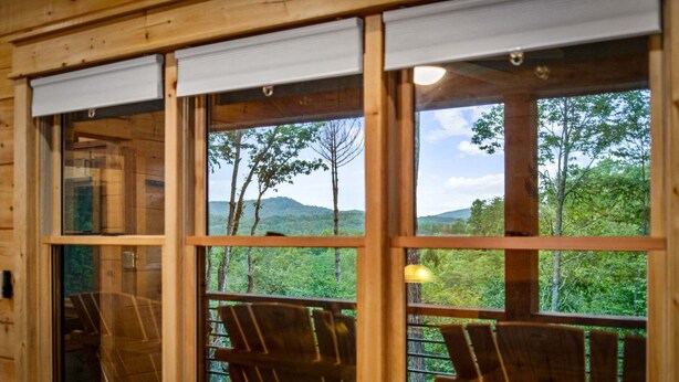 Eine Holzhütte mit großen Fenstern, Holzwänden und zwei Holzstühlen.