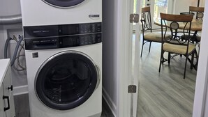 Un grand appareil combiné lave-linge et sèche-linge blanc, à deux portes, doté d’un panneau de commande et d’une étiquette indiquant la mention « DRYBOOST ».
