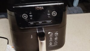 A kitchen appliance, possibly a rice cooker, with a control panel and a power cord plugged in. - Charming 1-bedroom apartment in amazing Syracuse with AC and heat (Syracuse)