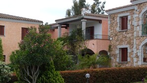A building with stone and stucco exterior, multiple balconies, and lush greenery. - Wonderful view of the island of Tavolara (Monte Petrosu)