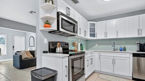 A modern kitchen with white cabinets, stainless steel appliances, and a tiled backsplash. - Harbor Haven in Fort Lauderdale (Fort Lauderdale)