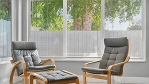 Two grey cushioned chairs with wooden frames and a small ottoman in front of a window with blinds. - Harbor Haven in Fort Lauderdale (Fort Lauderdale)