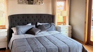 A bedroom with a large bed, wooden ceiling, and a ceiling fan.
