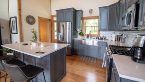 A modern kitchen with grey cabinets, stainless steel appliances, and a central island with bar stools.