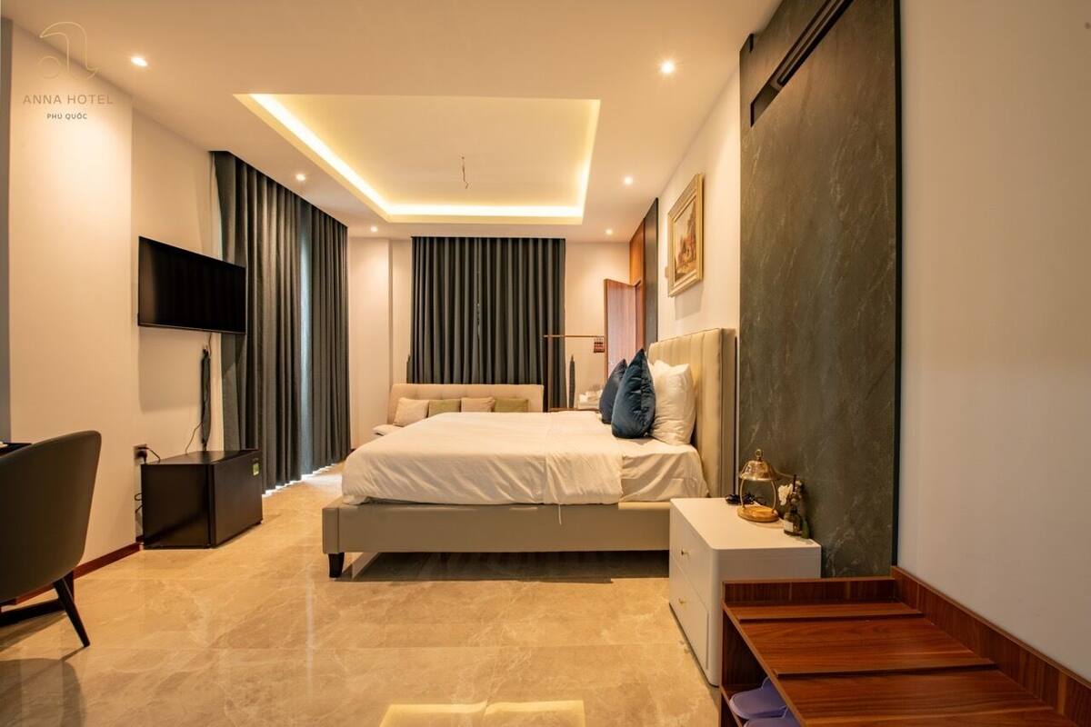 A modern hotel room with a bed, a TV, a desk, and a chair.