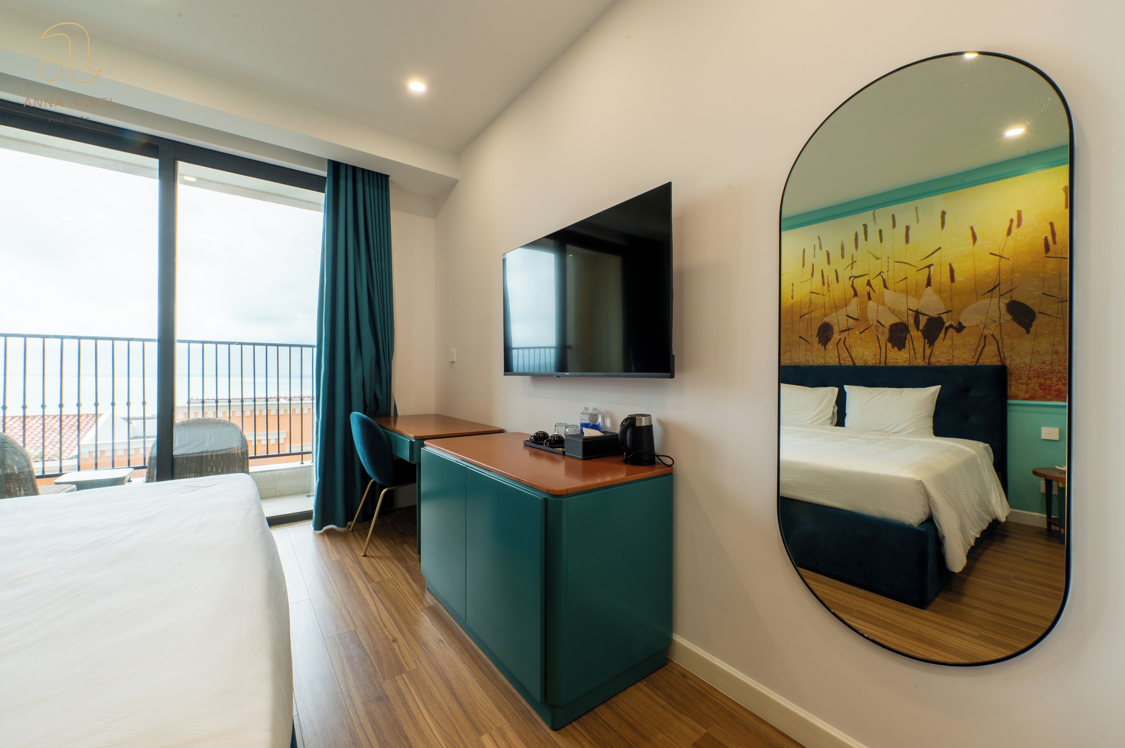 Habitación de hotel con cama, escritorio, silla, un espejo grande y balcón con vistas.