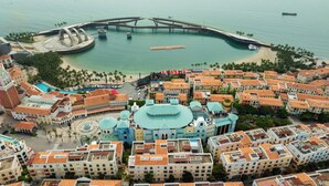 An aerial view of a coastal city with a prominent blue-domed building, a bridge, and a beach. - Anna Hotel Phu Quoc - Sunset Town Tour - Infinity Pool Access (Phu Quoc)