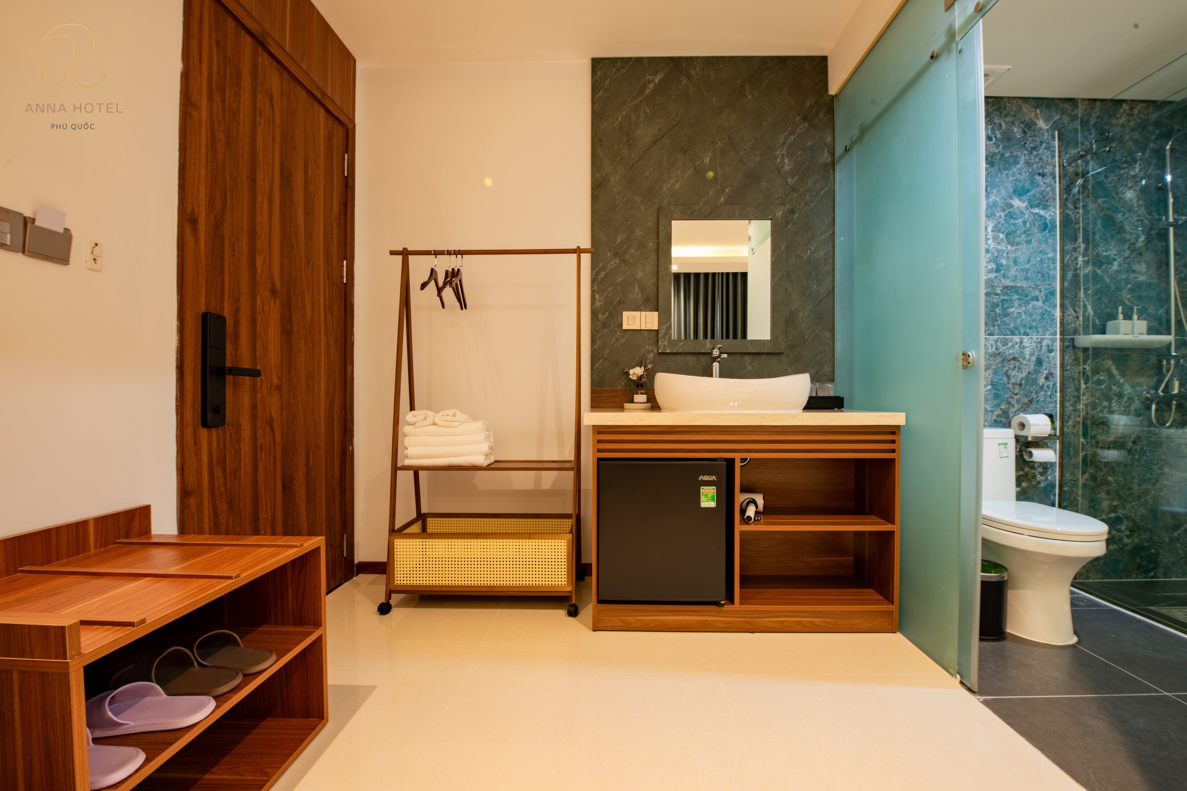 Un baño moderno con tocador de madera, cabina de ducha de vidrio y zapatero.