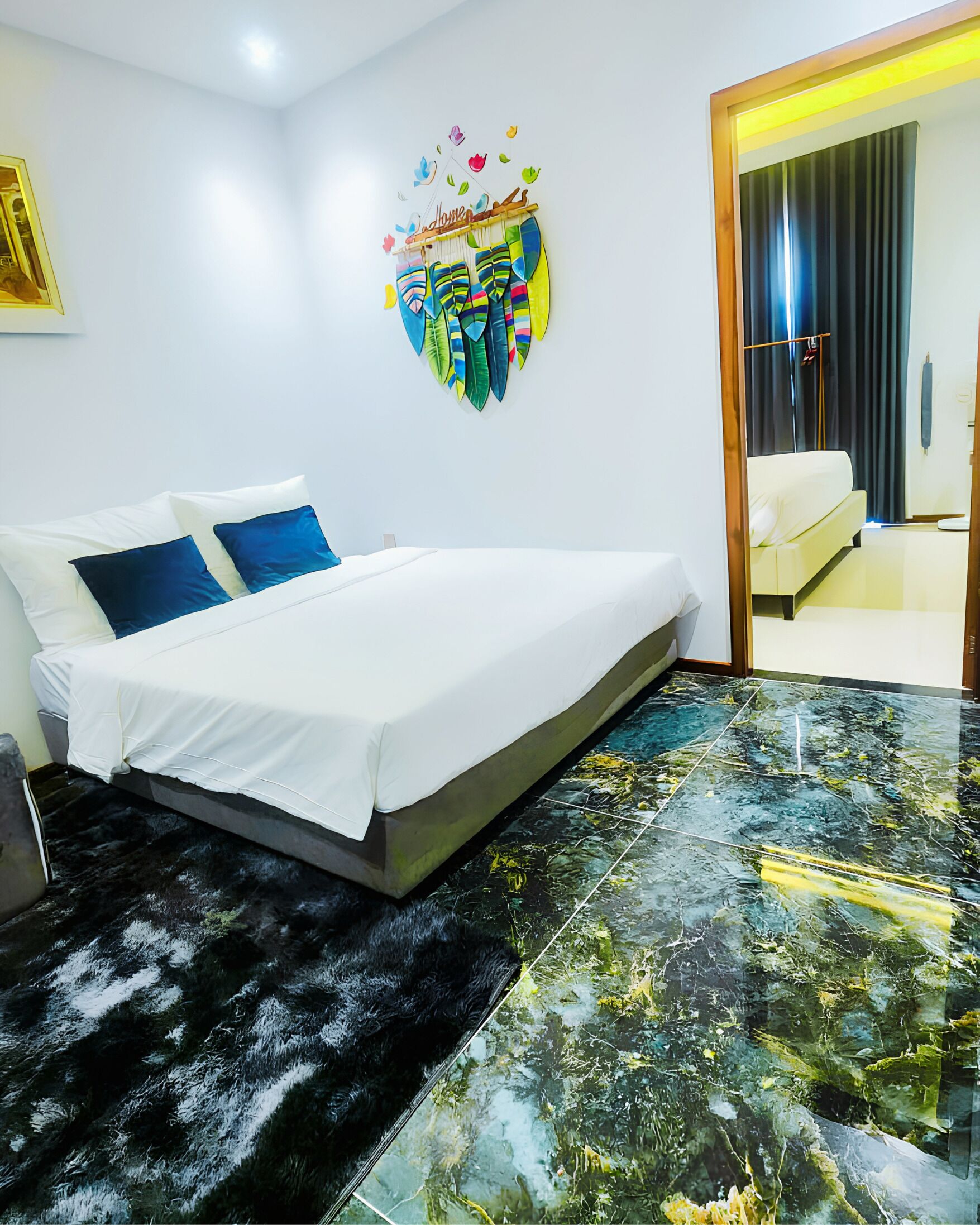 A bedroom with a bed, a rug, a wall art piece, and a view of another room.