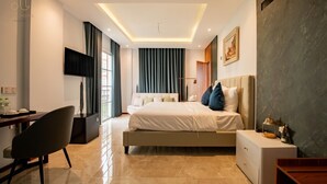A modern hotel room with a large bed, a desk with a chair, a flat-screen TV, and a large window with curtains. - Anna Hotel Phu Quoc - Sunset Town Tour - Infinity Pool Access (Phu Quoc)
