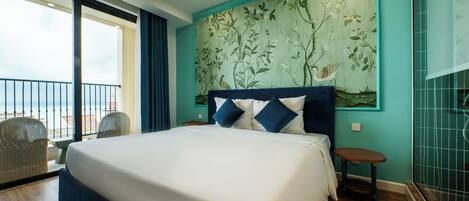 A hotel room with a large bed, a balcony with wicker chairs, and a mural on the wall.