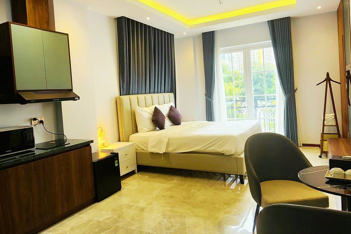 A modern hotel room with a bed, a TV, a desk, and a chair.
