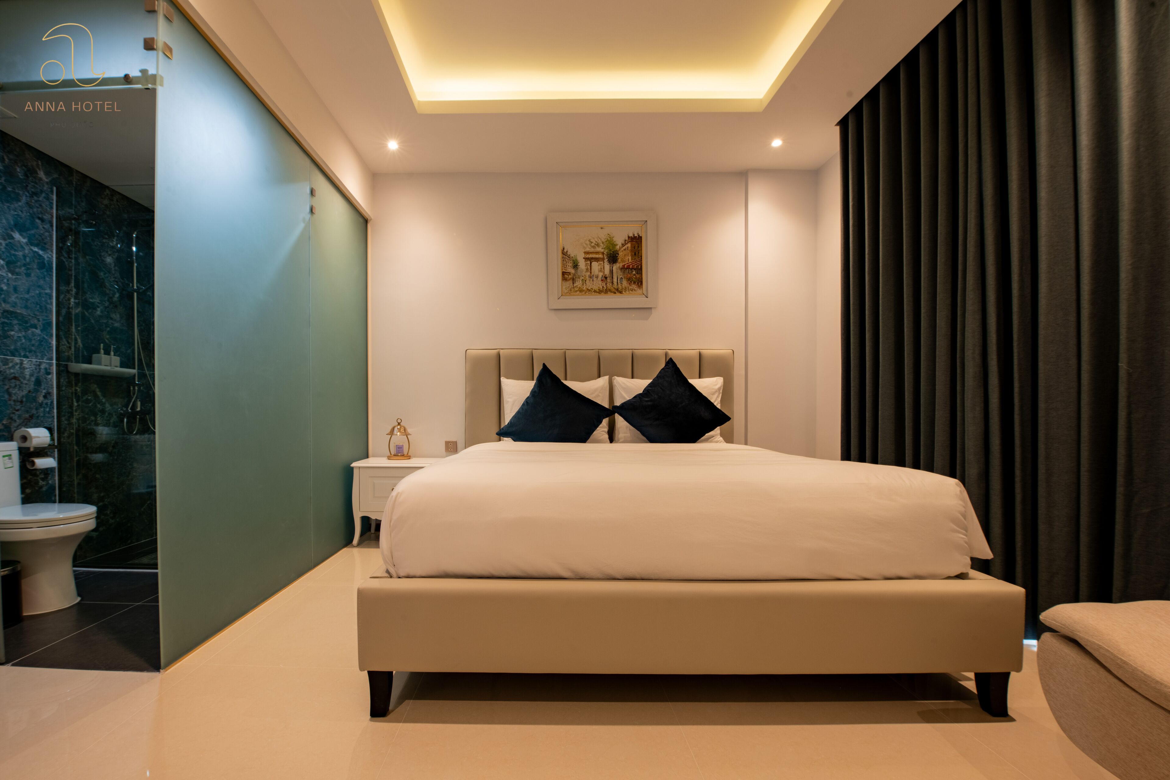 Um quarto de hotel moderno com uma cama grande, uma mesinha de cabeceira e um criado-mudo.