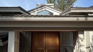 Una casa con puerta principal de madera, fachada blanca y una escalera que lleva a la entrada.