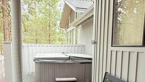 Un porche cubierto con un banco de madera y un jacuzzi.