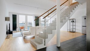 Un salon moderne avec un escalier, un canapé, une table basse et un lampadaire.