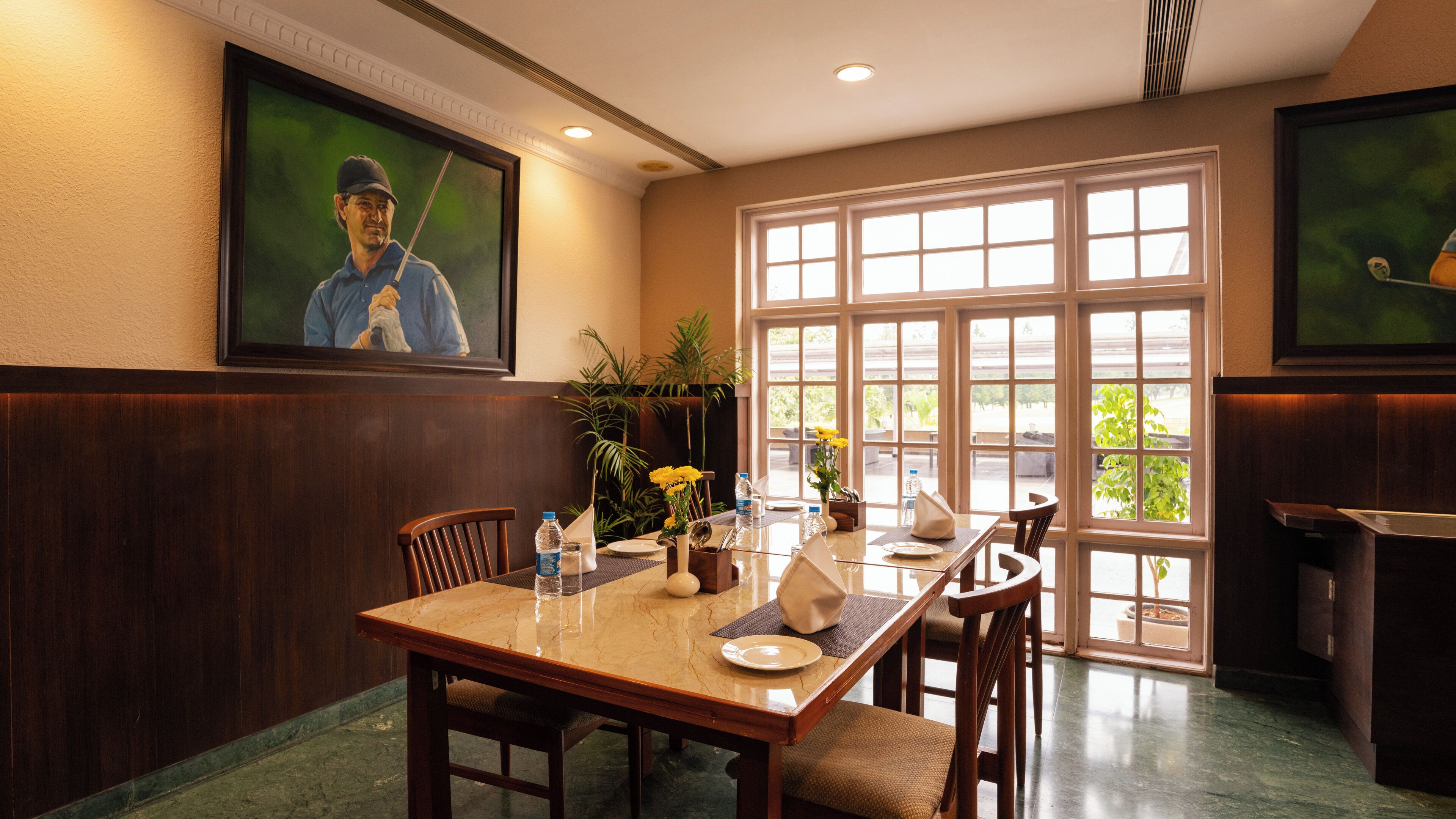 A dining area with a wooden table, chairs, and a large window with a view of greenery.