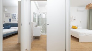 Et moderne hotelværelse med seng, et lille skrivebord, badeværelse med bruser og udsigt over byen.