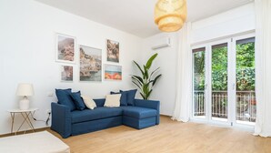En moderne stue med en blå sofa, en hvid lampe og billeder i rammer på væggen.