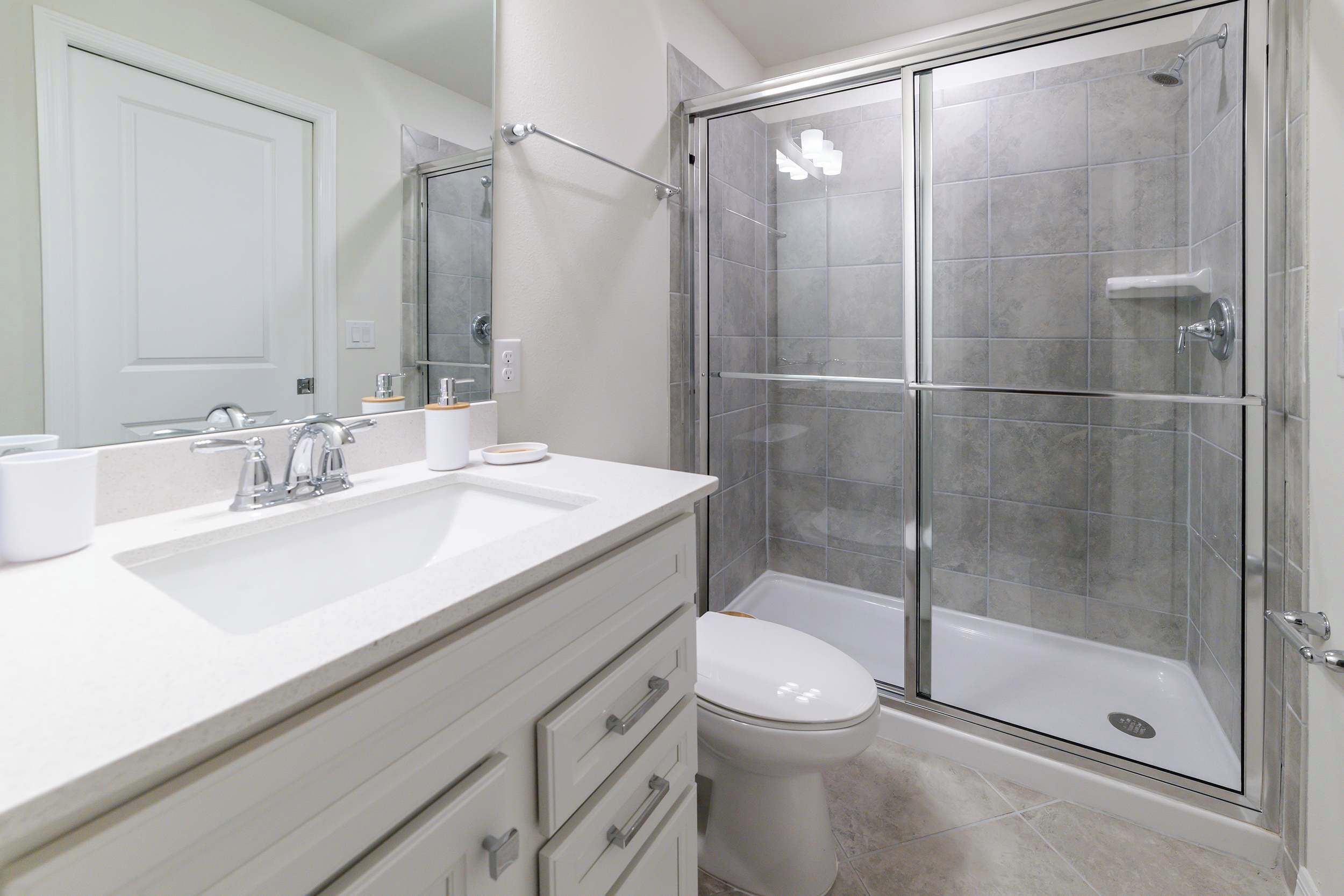 Une salle de bain moderne avec une douche à parois de verre, un lavabo blanc et des toilettes.
