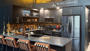 Et moderne køkken med en central ø, barstole og et skilt over øen, der står "The Lofts @ Frostfire".