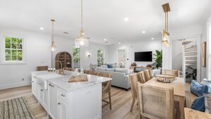 A spacious living area with a large island, wooden dining table, and a comfortable sofa. - Second Wind - Rosemary Beach - Private Pool, Access to Private Beach, Fitness and Tennis Access! (Rosemary Beach)