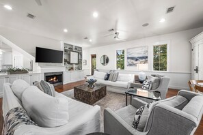 A modern living room with a fireplace, white sofas, a coffee table, and a flat-screen TV. - Blu Manor Cottage & Carriage House - Access to 4 community pools, private beach, fitness and tennis! (Rosemary Beach)