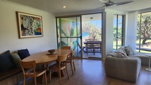 A dining area with a wooden table and chairs, a sofa, and a painting on the wall.